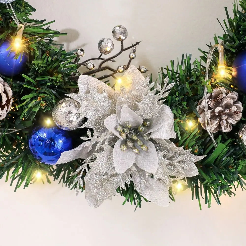 Närbild på julkransens rosett och blå julstjärnsblommor
